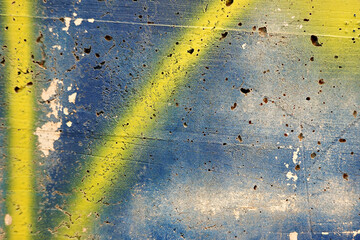 Grunge weathered stucco wall with painting strokes and spray in blue and yellow colors. Part of old...