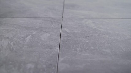 Smooth camera movement revealing intricate gray tile surface, capturing detailed texture and geometric pattern of architectural flooring material