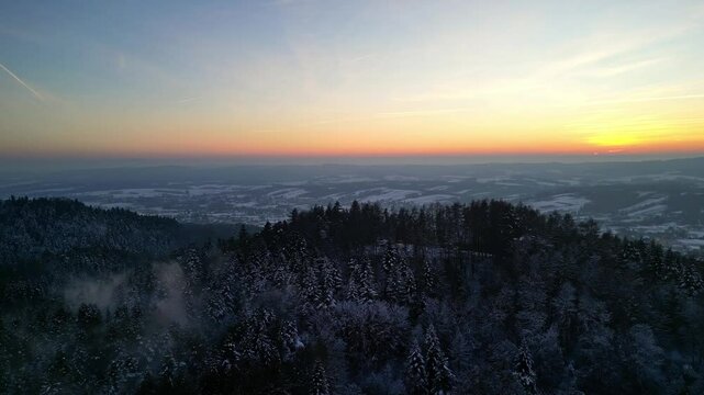 Majestic Winter Sunset Over a Snow-Covered Forest in Blizne, Bathed in a Gentle Mist &ndash; A Breathtaking View in Southern Poland
