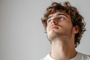 A european man with curly hair gazes thoughtfully to the left, lost in contemplation in a softly lit indoor space