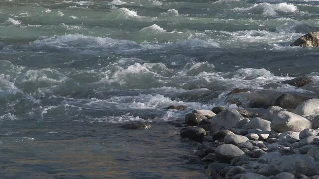 Seething water quickly flows over the stones. Mountain river in autumn, slow motion