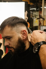 Barbershop. Unrecognizable male barber hands making customer Fashionable haircut in Modern style barber shop. Bearded Man client visit gentleman grooming beauty salon for hairstyle care