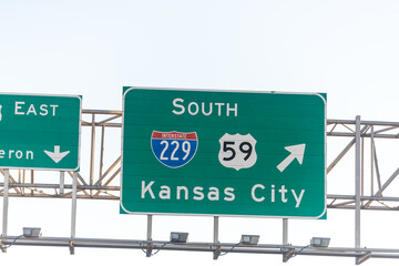 Green road signs in Kansas south for city exit on interstate highway 229 south and east against blue sky