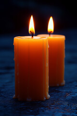 Two lit candles with wax dripping down the sides, glowing against a dark backdrop.
