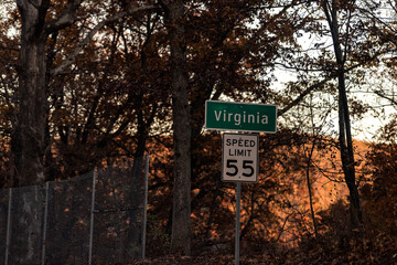 Virginia state line welcome sign on rural countryside road highway in autumn fall with speed limit for 55 miles per hour