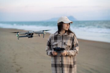 Obraz premium Woman photographer landing or taking off a drone on seaside