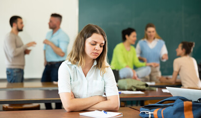 Portrait of a student girl sitting at desk with a pen and a copybook during a study break, preparing for classes in the ..university auditorium