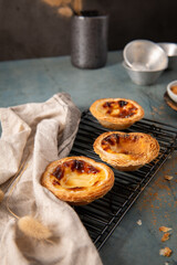 Golden-brown Portuguese custard tart on a rustic metal tray