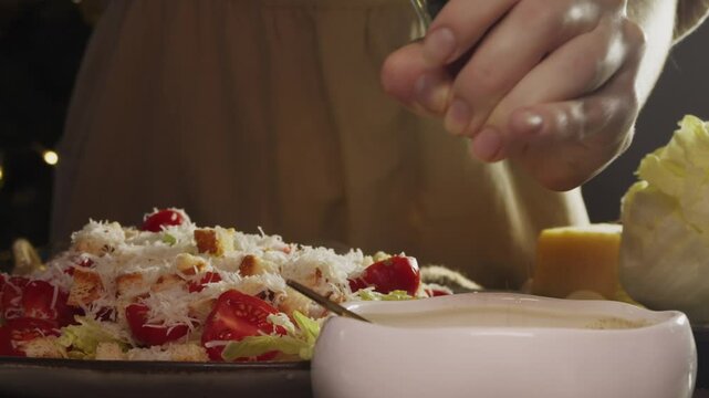 Chef preparing Caesar salad adds seasoning and pepper from pepper mill to sauce. After sprinkling with pepper, sauce becomes savory and delicious delight.