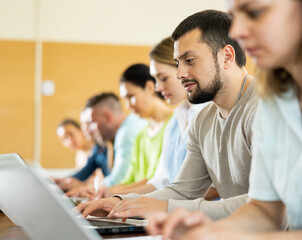 Fototapeta premium Portrait of a student guy studying on a laptop during a class in a university auditorium