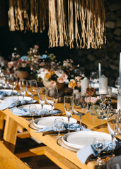 A beautifully set rustic wooden dining table adorned with elegant glassware, white plates, and blue napkins.