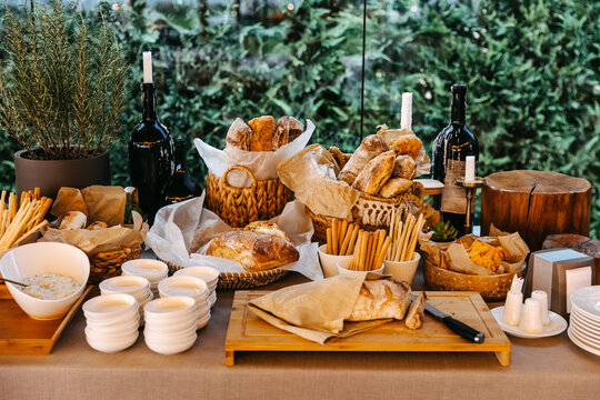 Elegant rustic bread and snack table with fresh artisanal bread and breadsticks.