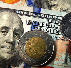 Closeup of Canadian coins on a US hundred dollar bill
