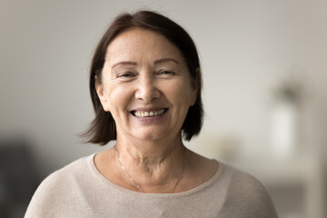 Portrait of pretty elderly woman smiling warmly look at camera, exudes contentment and wisdom,...