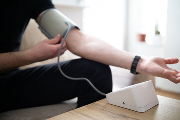 Young man measuring blood pressure at home close up