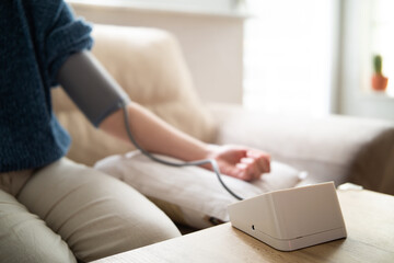 Young woman measuring blood pressure at home close up