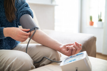 Young woman measuring blood pressure at home close up