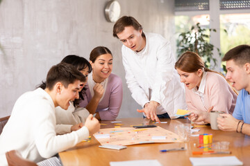 Happy girls and boys play board games in classroom