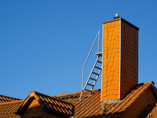 Rooftop Architecture: Orange Chimney with Ladder and Clear Blue Sky