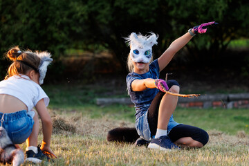 Cute young little kid girl wear cat furry mask enjoy have fun playing outdoors in forest street...