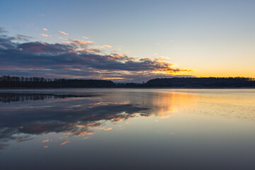  Serene lake under a blue sky
A peaceful lake with clear blue skies and a distant forest, reflecting tranquility and natural beauty.