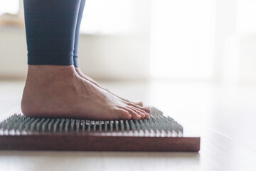 Yoga woman legs standing on nails with singing meditation bowl top view closeup