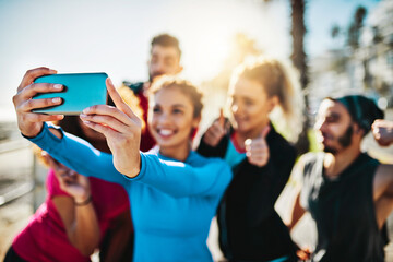 Obraz premium Hands, phone and friends take selfie for fitness to post picture for workout, wellness or health on social media. Exercise team, happy people or photo together for memory, sports or thumbs up outdoor