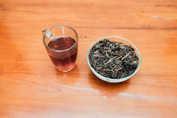 A glasses of hot tea with dry tea in a glass bowl on the wooden table. Concept of advertising tea...