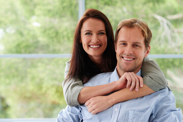 Naklejka premium Couple, portrait and happy hug in home, support and together for security in relationship. People, embrace and love for marriage in living room, comfortable and care to connect for healthy commitment