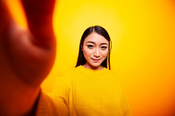 Smiling asian female individual holding the camera, making a video for her online audience....