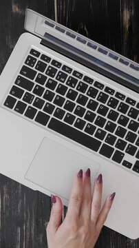 Close-up of a woman developer hands using a laptop touchpad while working at a table in an office. Modern tech work and precision in action. Vertical video.