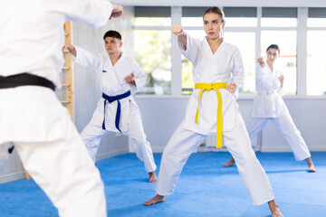 Group of men and women in kimonos train karate techniques in studio.. © JackF