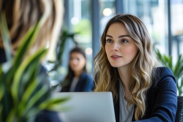Female professional wearing business clothing and having discussion with colleague during office meeting.