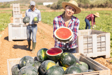 Fototapeta premium Female farmer with half a watermelon in her hands posing in a farmer field