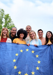 Vertical. Multiracial group of friends holding the European Union flag with pride, symbolizing...
