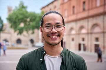 Handsome happy bearded Asian man. Portrait of cheerful young male Chinese standing outdoors and...