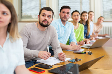 Group of attentive students studies in the university auditorium during class, writing lecture in copybooks