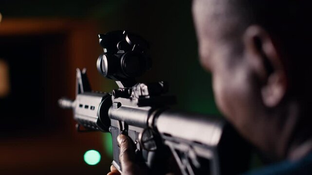Man holds assault rifle, enjoying recreational shooting experience in firing range. Person practices with semiautomatic weapon in safe environment at shooting range company, camera B extreme close up