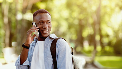 Portrait of handsome African American man talking to his friend on cellphone at green park