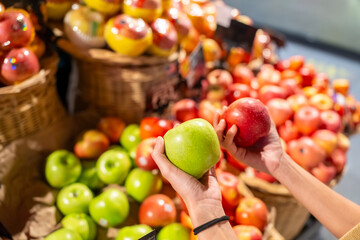 Happy Asian woman shopping and buying organic safety food at supermarket. Woman customer enjoy healthy lifestyle choosing apple fruit and food reading product labels and checking price on shelves.