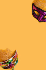 Festive face masks for carnival celebration on colored background with copy space