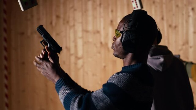 Man holds pistol, enjoying recreational shooting experience in firing range next to instructor reloading weapons. Employee loading firearms for shooting range company customers, camera B