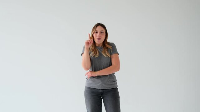 Curious young Caucasian woman contemplating and having brilliant idea or solution, standing on on white background and pointing finger up. Innovation, eureka, brainstorm concept.