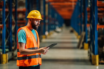Warehouse worker using tablet managing inventory and logistics in large distribution center