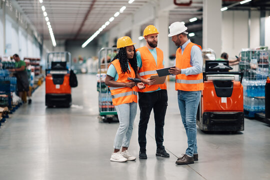 Warehouse workers discussing logistics using digital tablet and barcode scanner