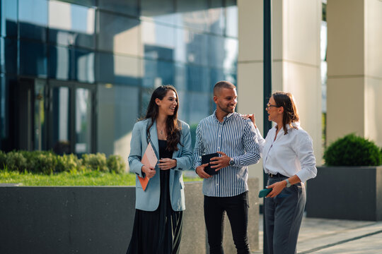 Three businesspeople having a conversation walking outside modern office building