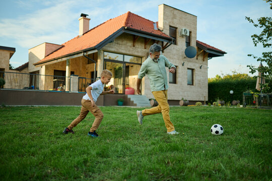 Grandfather and grandson playing soccer in backyard