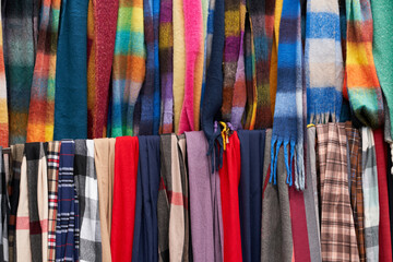 Colorful collection of scarves displayed at a market during the day showcasing various patterns and textures