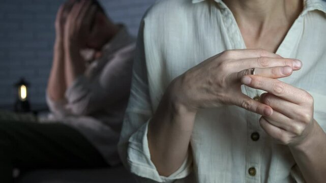 Disappointed woman with gold ring. A view of stressed wife takes off her marriage ring by the disappointed husband indoor.