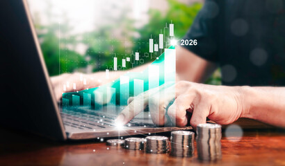 A man is using a laptop to analyze his company's profit in 2026 using a digital virtual graph....